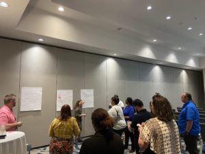 Mindy Bohannon presenting to a crowd of attentive listeners during a conference.