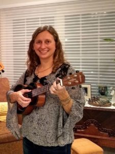 Mindy smiling while holding a ukulele.